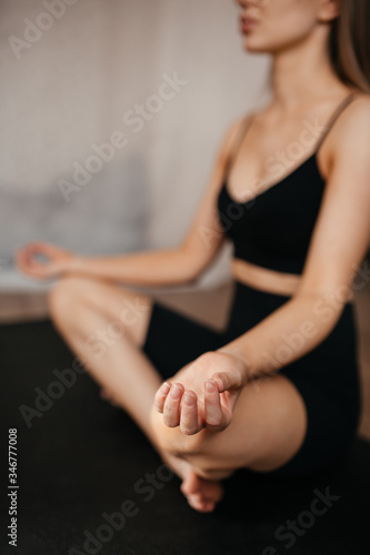 close-up shot of a beautiful girl who meditates at home sitting on a black rug in black clothes