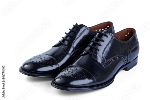 Men's classic shoes made of glossy black patent leather on laces with perforated pattern. Top view at an angle.