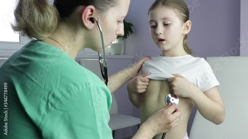 Family modern woman doctor in the office listens to the lungs of a child with a phonendoscope, a girl of Caucasian appearance of seven years. check for coronavirus, covid-19