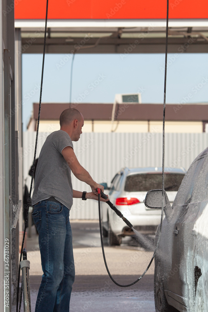 Male worker wash the car with high pressure washer