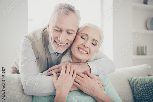 Close up photo of charming spouses have passion cuddling with closed eyes dressed turquoise jumper sit divan in house