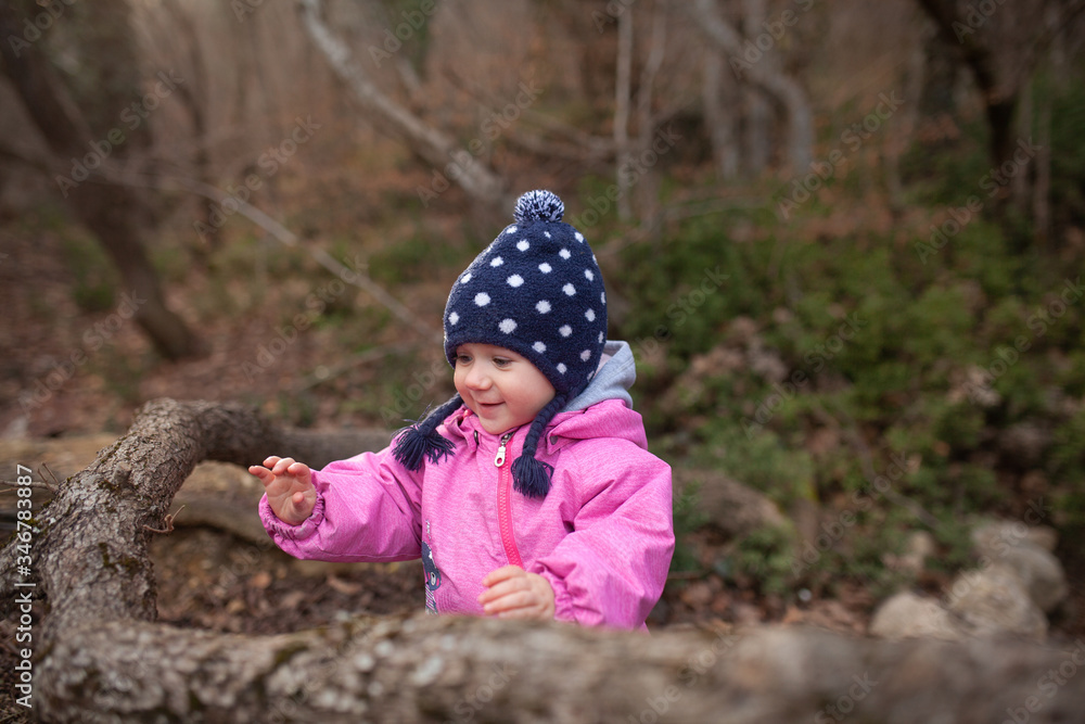 A small child walks in the autumn forest, a girl dressed in a pink jumpsuit and a hat, fresh forest air is good for children's health A small child walks in the autumn forest, a girl dressed in a pink jumpsuit and a hat, fresh forest air is good for children's health