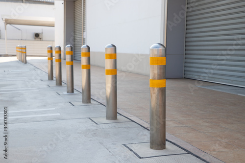 steel bollards with yellow reflec strip near footpath in front of the shutter door. photo