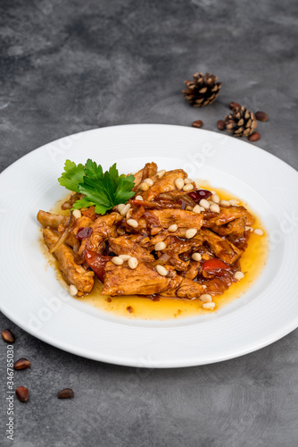 Cooked chicken fillet with pine nuts in a white plate