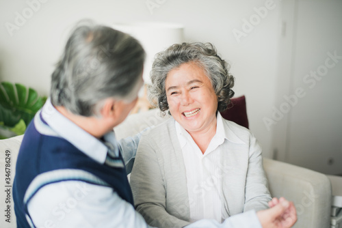 Wallpaper Mural Senior Asian couple love siting on sofa and looking at hand of man, Retired woman help man to Buttoned shirt which smiling and felling happy in living room at home. Celebration birthday concept Torontodigital.ca