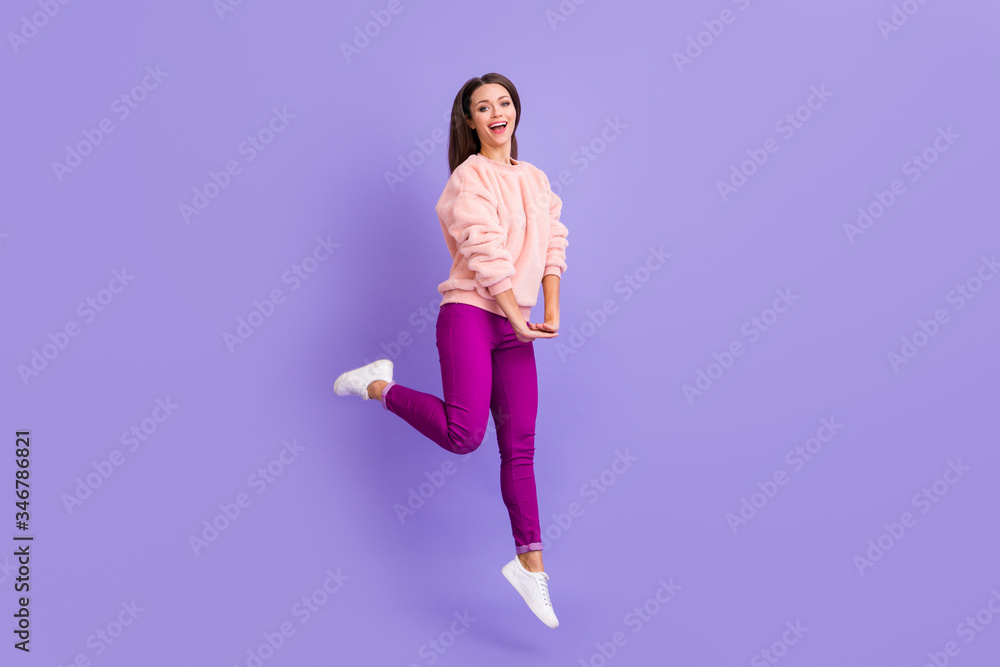 Full body profile photo of funny ecstatic lady jumping high up rejoicing spend lovely free time wear casual fur soft sweater pants sneakers isolated purple color background
