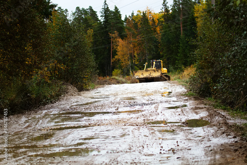 Crawler bulldozer rides on a dirt road photo