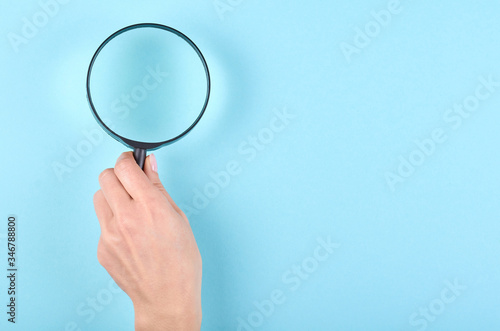 Black magnifying glass on blue background. photo