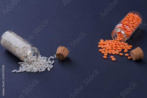 Two opened mini bottles with rice and lentils. Dark blue background.