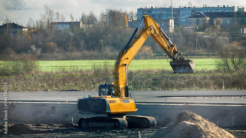 Excavator in the process of leveling the slope of the road photo