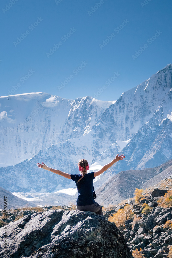 Happy young blonde woman in blue t-shirt sitting on a mountain top. Hiker relaxing on top of a mountain and enjoying sunny day. Happy young blonde woman in blue t-shirt sitting on a mountain top. Hiker relaxing on top of a mountain and enjoying sunny day.