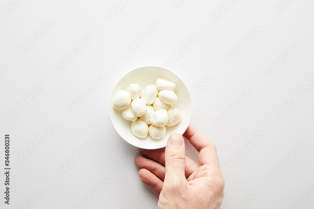 Cropped view of male hand with bowl with mozzarella on white background