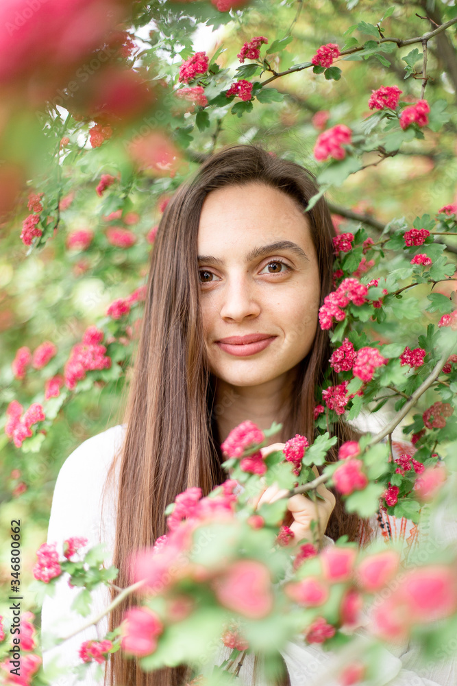 Portrait of beautiful young smiling woman against the background of a blossoming pink flowers hawthorn tree Portrait of beautiful young smiling woman against the background of a blossoming pink flowers hawthorn tree