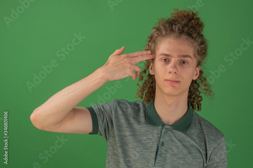 A handsome, young guy holds his finger to his temple. Headshot concept. Problems in the life of a man. Thoughts of suicide.