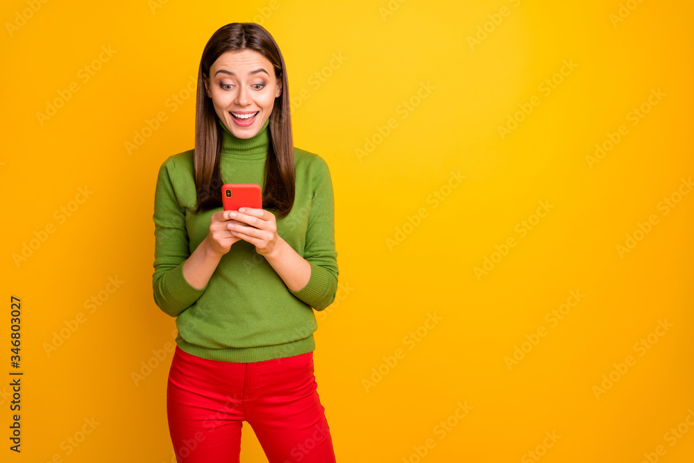 Portrait of crazy funky amazed girl using her smartphone reading social network news get like notification scream wow omg wear red pants trousers isolated over yellow color background Portrait of crazy funky amazed girl using her smartphone reading social network news get like notification scream wow omg wear red pants trousers isolated over yellow color background