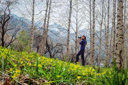 A man shoots a photo in the spring birch forest. Fresh young grass and wildflowers. Alma-Ata's region. Kazakhstan.