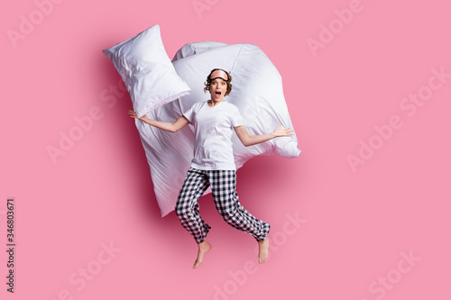 Full size photo of nice lady jump throw pillow up blanket flight slumber party open mouth wear sleep mask white t-shirt plaid pajama trousers barefoot isolated pink color background