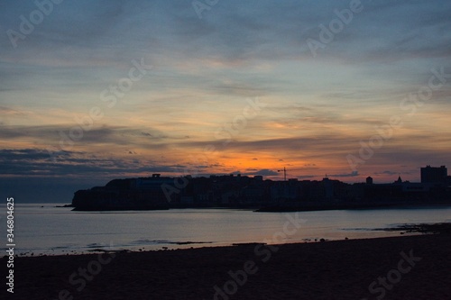 Playa de Poniente  Gij  n  con vistas al casco antiguo de Cimadevilla y al Elogio del horizonte. Durante el amanecer  con un deportista practicando paddle surf en el agua. Asturias  Espa  a.