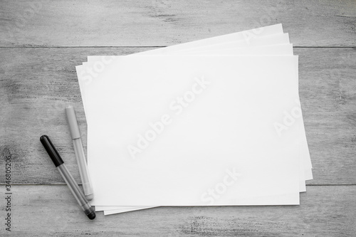A4 blank paper leaves and two pencils on a light wooden table top view of flat objects. Home workplace by the window