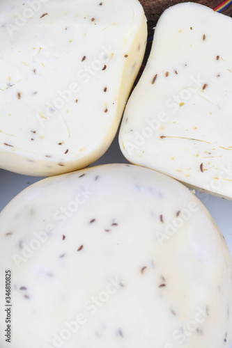 A variety of wheels of cheese seasoned with herbs for sale at the deli counter in the supermarket. photo