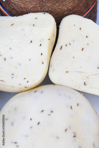 A variety of wheels of cheese seasoned with herbs for sale at the deli counter in the supermarket. photo