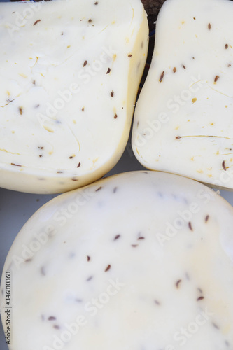 A variety of wheels of cheese seasoned with herbs for sale at the deli counter in the supermarket. photo