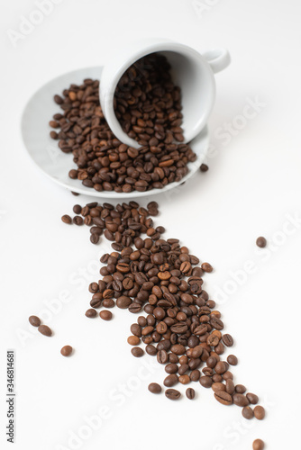 Cup оf coffee , white ceramic cup with scattered roasted coffee beans on a white background. Isolate. Space for text