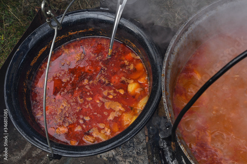 Very large cauldron cooking food during campfire. Cooking in a pot on the fire. Camping concept