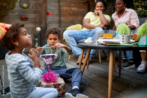 afro-american kids playing on a birthday party with their parents in the background. Family concept