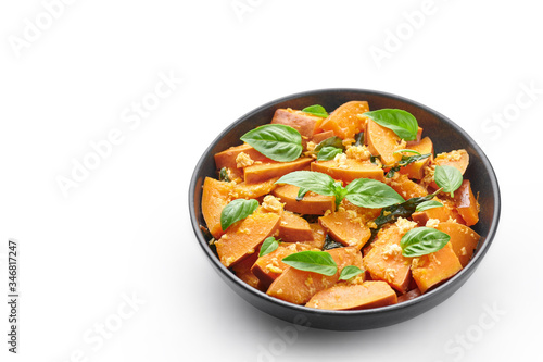 Pad Faktong or Thai Stir-fried Pumpkin in black bowl isolated on white background. Pad Phuk Tong is thailand cuisine dish with sliced Kabocha Squash, eggs or tofu and basil. Thai Food. Copy space