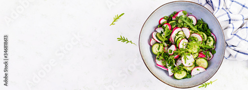 Vegetarian vegetable salad of radish, cucumbers, arugula and green onions. Healthy vegan food. Top view, overhead, banner