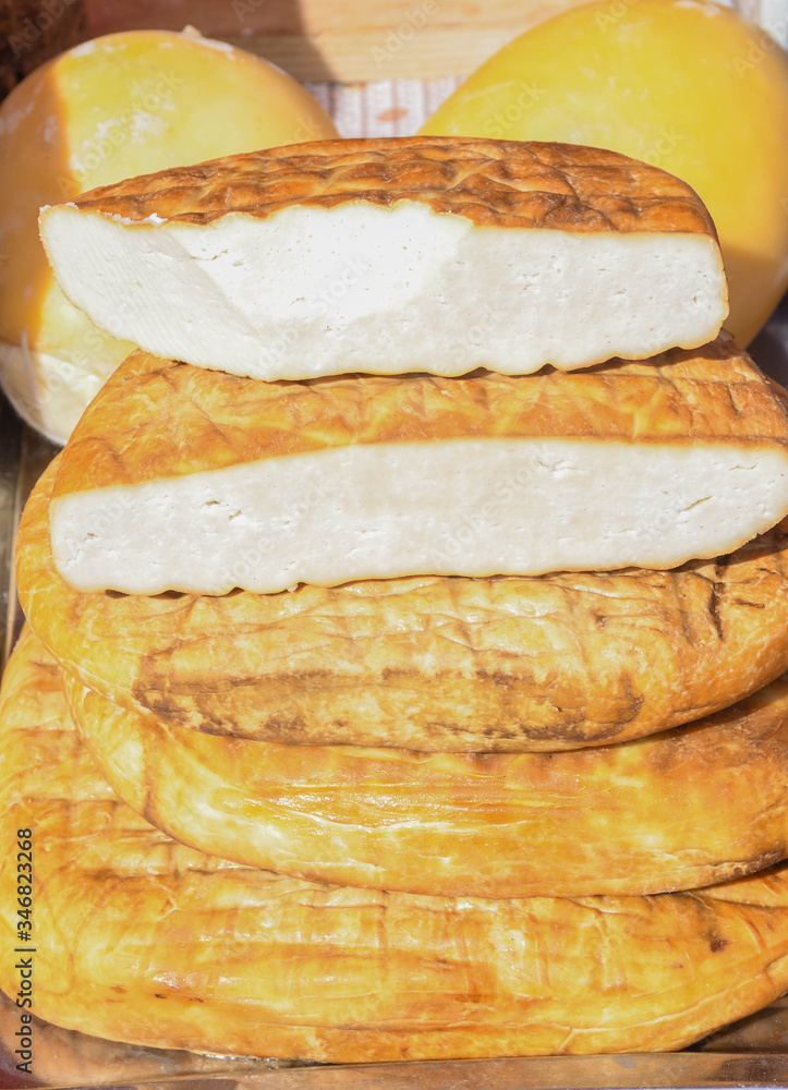 A variety of wheels of cheese seasoned with herbs for sale at the deli counter in the supermarket. A variety of wheels of cheese seasoned with herbs for sale at the deli counter in the supermarket.