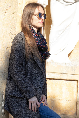 Fashionable girl posing on a wooden background.building with yellow brick. Spring weather, sunny day. Warm day.