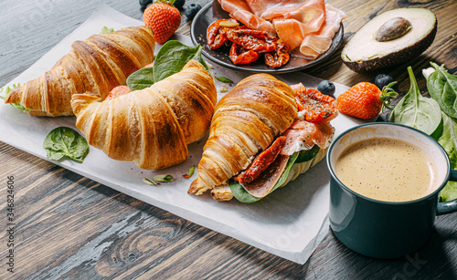 The concept of a hearty and tasty breakfast of fresh classic croissants with a variety of toppings from ricotta jamon avocado, strawberries, sun-dried tomatoes, and French mustard.