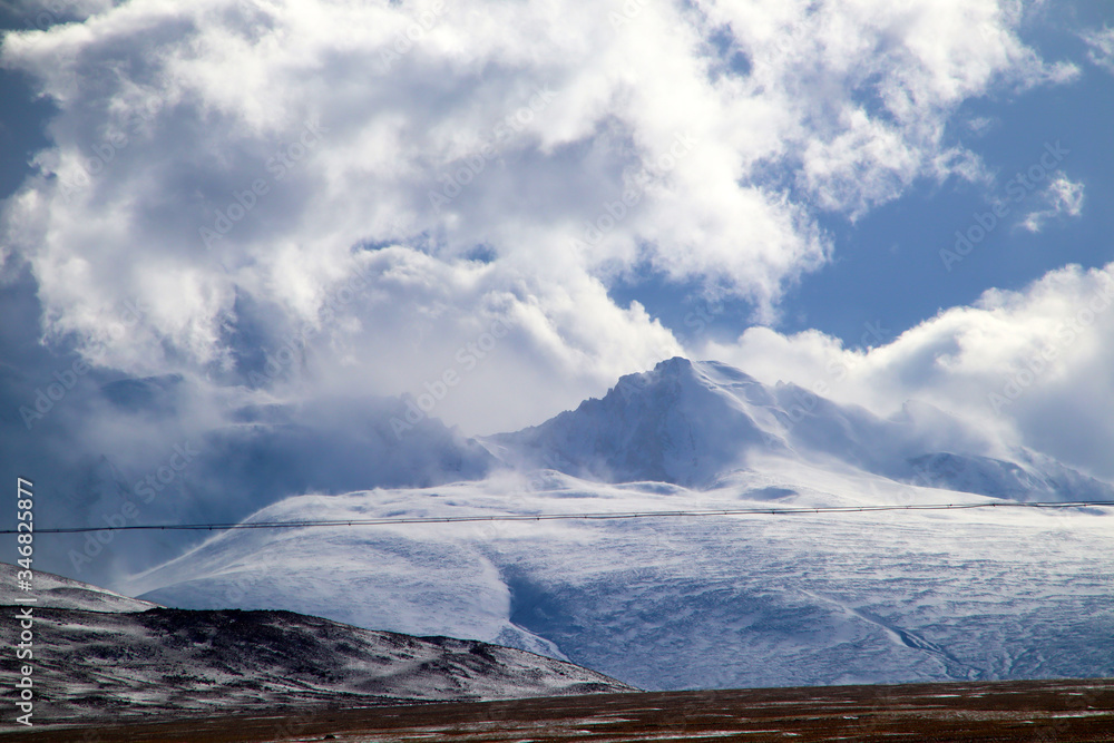 Fototapeta premium Plateau, high-voltage transmission tower, blue sky and white clouds, ice lake and distant Shishapangma Peak