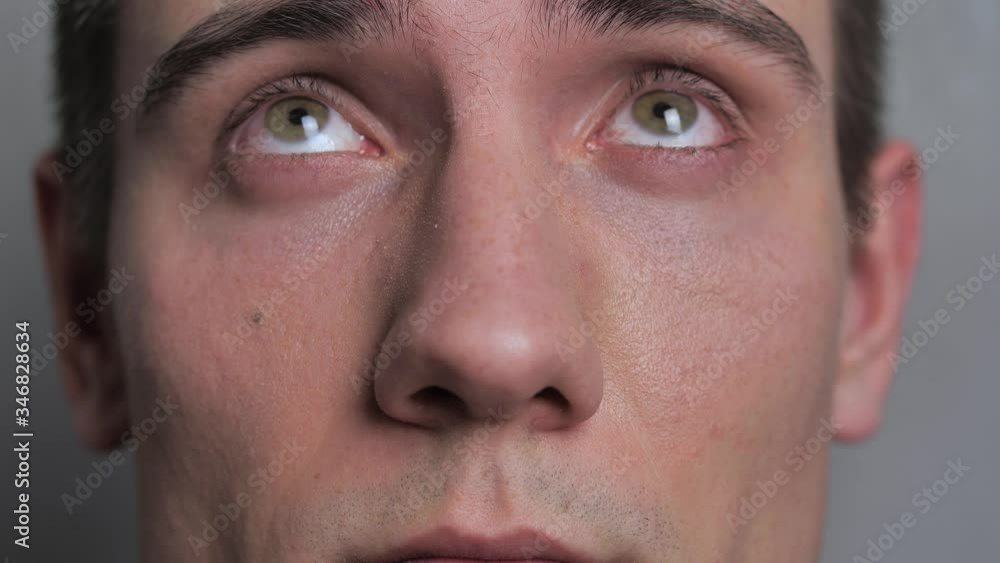 Close up of young mans eye looking into camera at isolated white background Close up of young mans eye looking into camera at isolated white background