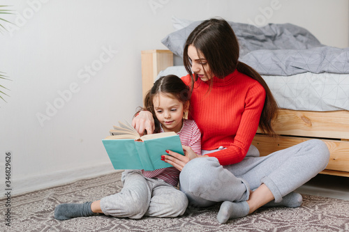 Foto Happy family mother and child daughter reading holding book lying in bed, smilin