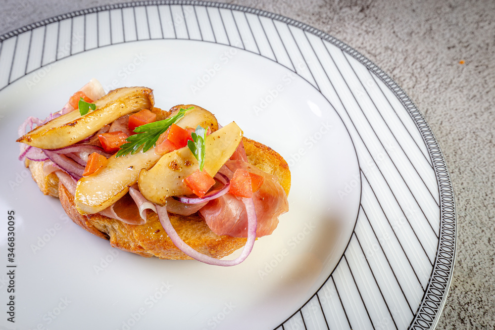 Bruschetta with proscuitto ham, tomatoes and King oyster mushroom. Iitalian style food