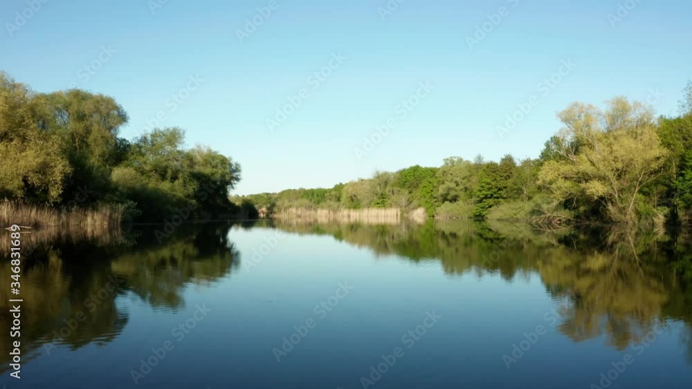 Slow dolly on a small lake with blue sky and lots of nature Slow dolly on a small lake with blue sky and lots of nature