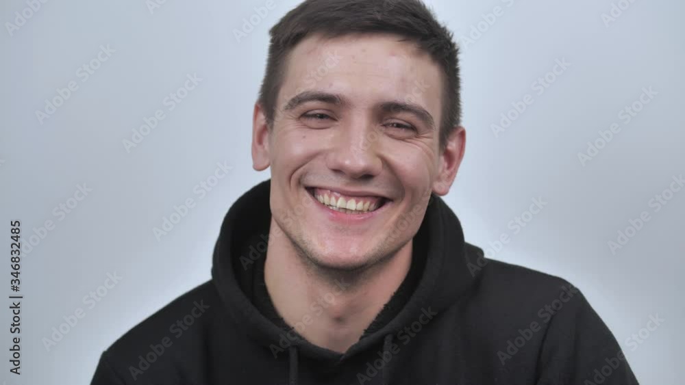 Attractive guy smiles sincerely, looking at the camera, isolated on white blurred background. Close up. 4k Attractive guy smiles sincerely, looking at the camera, isolated on white blurred background. Close up. 4k