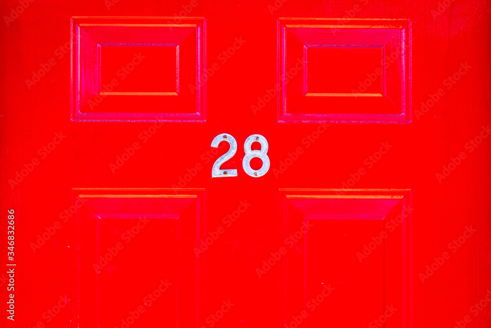House number 28 on a red wooden front door in London House number 28 on a red wooden front door in London