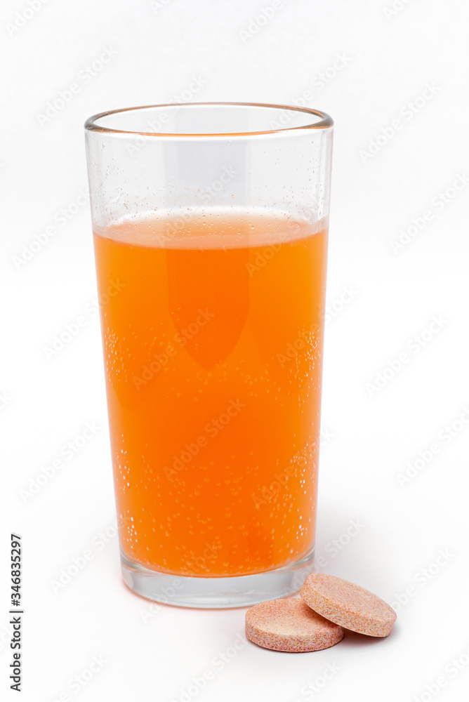 soluble effervescent multivitamins near a glass with vitamin in water on a white background soluble effervescent multivitamins near a glass with vitamin in water on a white background