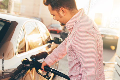 Young man refueling his car at a gas station .Self-service. Selective focus. Sunset light