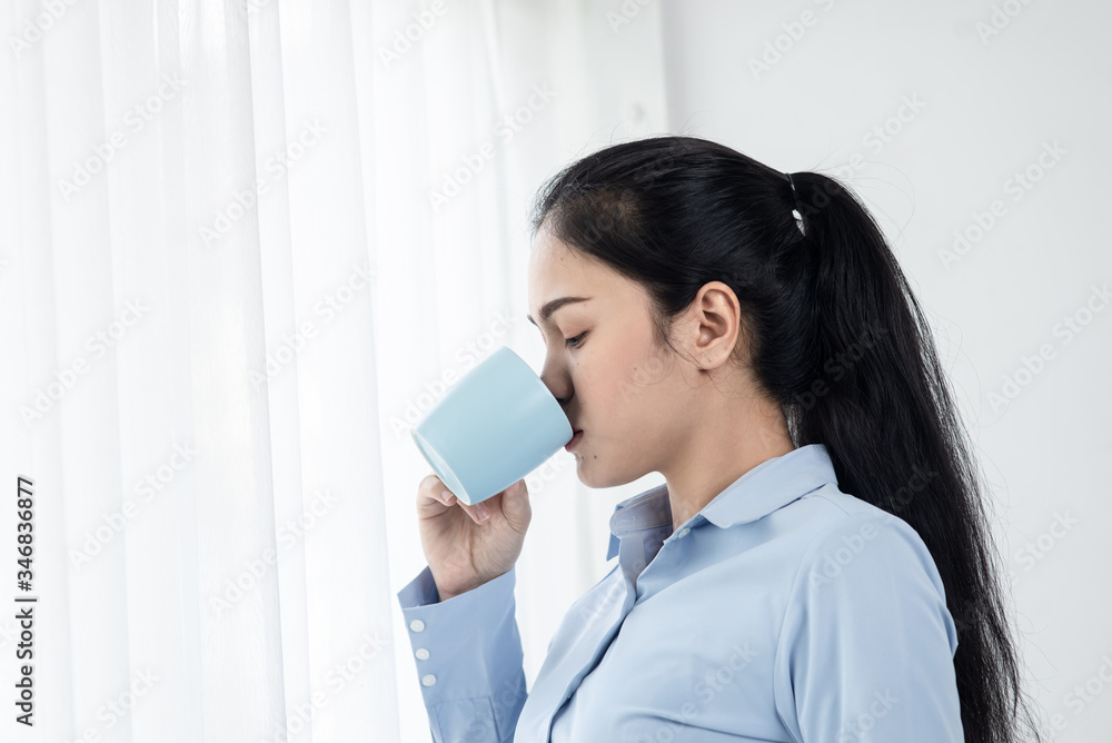 Asian business woman drinking coffee near window in the morning, lifestyle concept. Asian business woman drinking coffee near window in the morning, lifestyle concept.