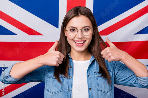 Close-up portrait of her she nice attractive lovely charming glad cheerful cheery girl recommending university college courses showing thumbup deal done isolated over british stripes flag background