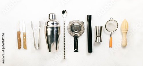 Steel bar tools and accessories for making cocktail. Shaker, jigger, strainer, spoon, tongs, muddler. Alcohol drink and beverages preparation concept. White background, top view, copy space
