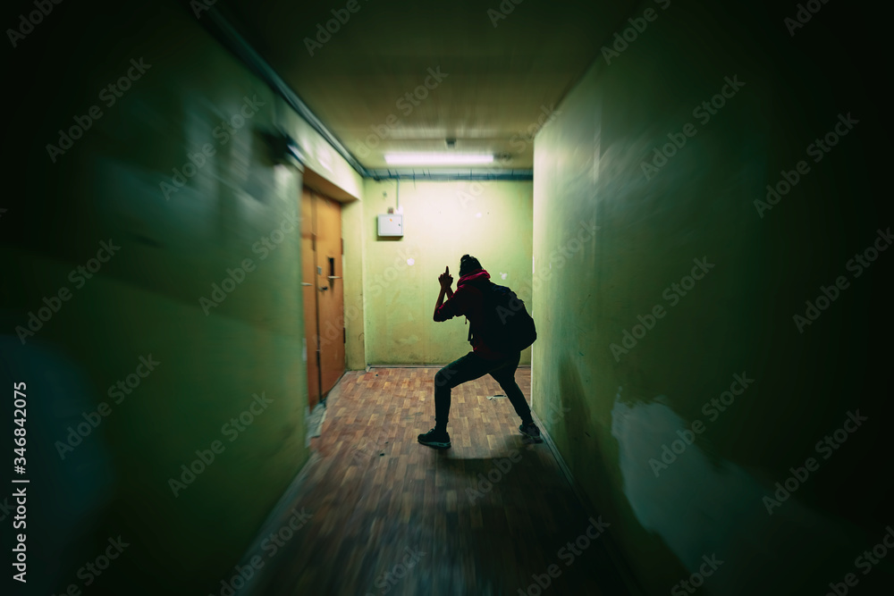 Girl silhouette imitates playing a spy with a gun. Dark corridor. Lurking, Sneaking, Scary