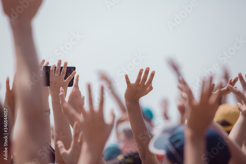 group of happy young people with hands up to the sky