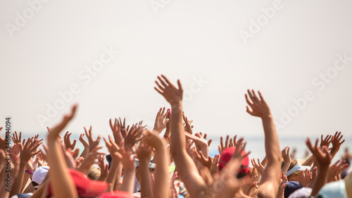 group of happy young people with hands up to the sky