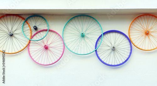 Old bicycle wheels colorful on the wall of a rental and repair shop, hipster decorative trend concept photo